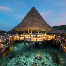 Outdoor restaurant at Hilton Moorea Lagoon Resort & Spa during sunset, with a tropical open-air dining area and warm evening views overlooking the beautiful Moorea surroundings.