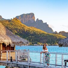 View of InterContinental Tahiti Le Moana Resort, featuring overwater bungalows overlooking the turquoise lagoon with majestic mountains rising in the background.