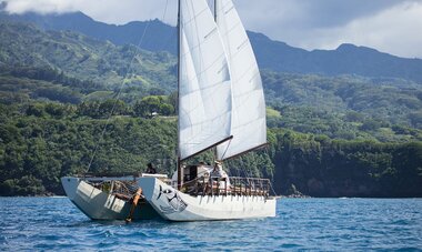 Vue sur un voilier naviguant devant des montagnes 